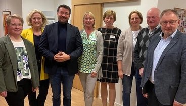 Eine gemischte Gruppe aus Mitgliedern der CDU und des Ludgerus-Werk schauen in die Kamera. Sie stehen im beleuchteten Flur des Seniorentreffpunkts.