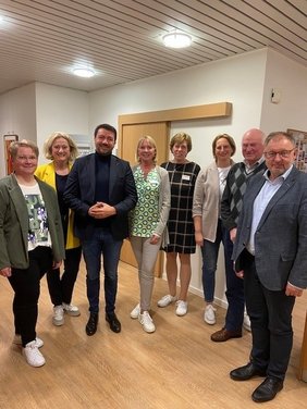 Eine gemischte Gruppe aus Mitgliedern der CDU und des Ludgerus-Werk schauen in die Kamera. Sie stehen im beleuchteten Flur des Seniorentreffpunkts.