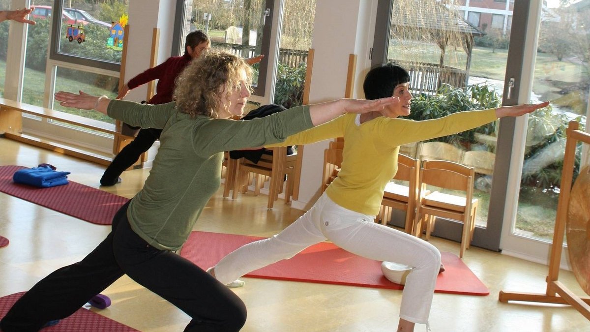 Ein Yogakurs im Ludgerus-Werk. Zwei Frauen im Vordergrund machen mit erhobenen Armen die gleiche Figur. Im Hintergrund ist eine weitere Frau, die das gleiche macht. 