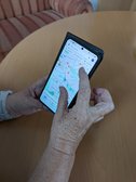 Ältere Hände halten ein Smartphone in den Händen. Auf dem Display ist eine Kartenapp zu sehen.
