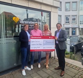 Vier Personen stehen vor dem Büro der Vereinsberatung in Lohne und halten einen symbolischen Check über 2000 Euro in den Händen. 